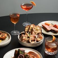 Una Una dinner table spread with multiple dishes including prawns, meat and fish, alongside cocktails